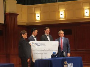 Four people hold a check for the first place winners of the Mayo business plan competition. The two people in the middle are the students that won.