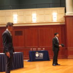 Two people standing up on a stage presenting their mayo business plan