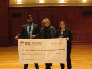 Three people holding up a check for the first place winners of the Mayo business plan competition